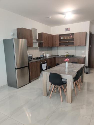 a kitchen with a table and a stainless steel refrigerator at Bella Qawra Maisonette in St. Paul's Bay