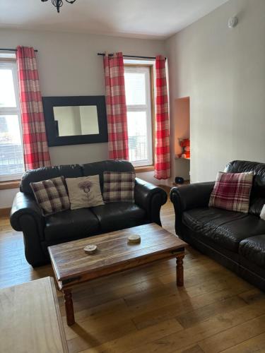 a living room with black leather couches and a coffee table at MacIver City Apartment Academy Street in Inverness