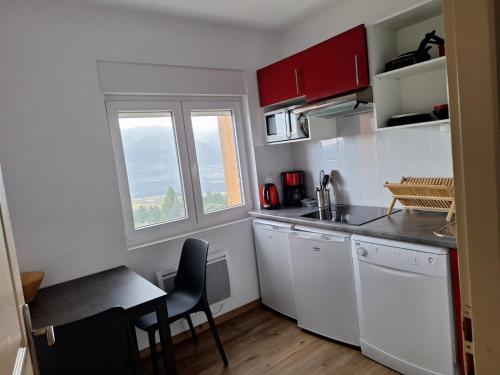 une cuisine avec des armoires blanches, une table et une fenêtre dans l'établissement Panoramic Campus, à Font-Romeu-Odeillo-Via