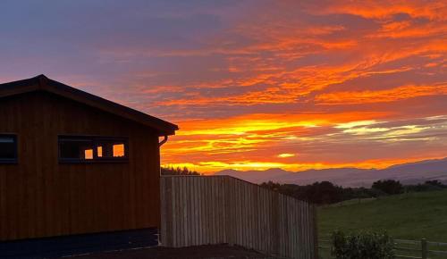 a sunset over a fence and a house at Arrochar View in Langbank