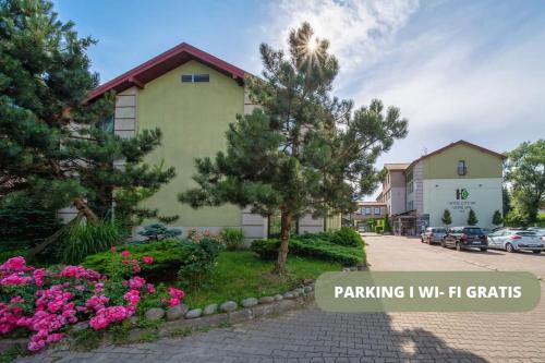 a building with flowers in front of a parking lot at Hotel City SM Business & Spa in Kraków
