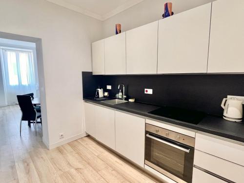 une cuisine avec des armoires blanches et un comptoir noir dans l'établissement Center 2 min walk to beach quiet sunny balcony, à Nice