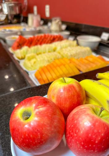 two apples and bananas on a plate on a table at Grande Hotel Petrópolis in Petrópolis