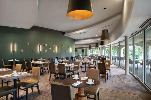 a restaurant with tables and chairs and windows at Dallas/Fort Worth Marriott Hotel & Golf Club at Champions Circle in Roanoke