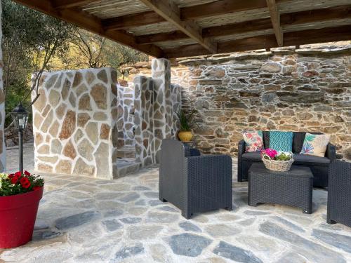 a patio with chairs and a stone wall at Bergerie tout confort L'immortelle in Saint-Florent