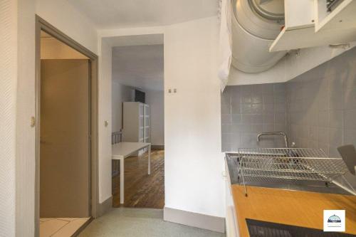 - une cuisine avec un évier et une porte menant à une chambre dans l'établissement Lescapade Hospitalière, à La Tronche