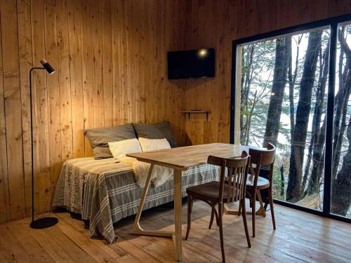 a room with a table and a bed and a window at Tiny house sobre el lago nahuel huapi in San Carlos de Bariloche