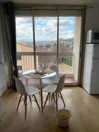 une cuisine avec une table et des chaises ainsi qu'une grande fenêtre dans l'établissement Superbe T 1 Greoux les Bains, à Gréoux-les-Bains