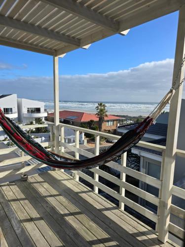 a hammock on a balcony with a view of the ocean at Atlantic Loft - Open plan apartment with Sea Views in Melkbosstrand
