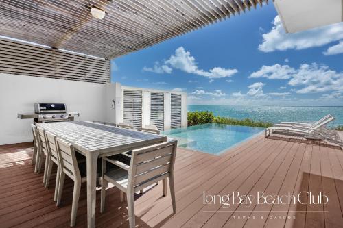 a dining table and chairs on a deck with the ocean at Long Bay Beach Club in Long Bay Hills