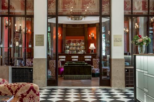 a lobby with a bar and a checkered floor at Hôtel de la Poste in Beaune