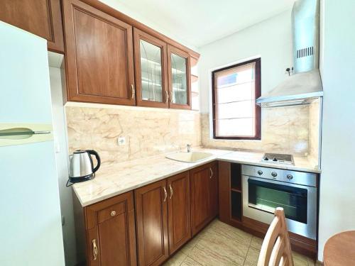 a kitchen with wooden cabinets and a sink and a stove at Аpartments Comfort -Marina Cape in Aheloy