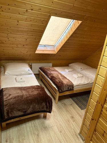 two beds in a wooden room with a skylight at Domki nad potokiem in Wetlina