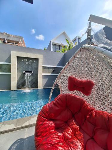 a hammock sitting in front of a swimming pool at Alzena villa batu in Batu