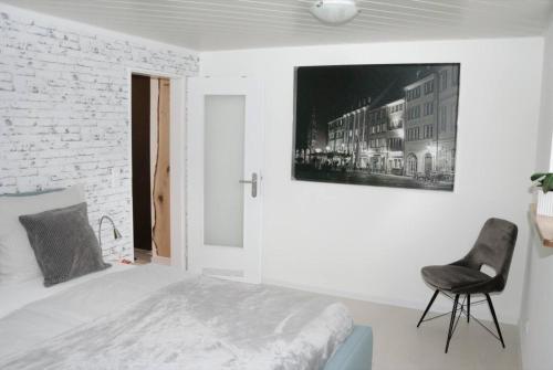 a white bedroom with a bed and a black chair at Ferienwohnungen Steiert in Freiburg im Breisgau
