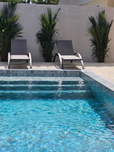 zwei Stühle neben einem Swimmingpool in der Unterkunft Nai Harn beach Villa 2 bdr in Rawai Beach
