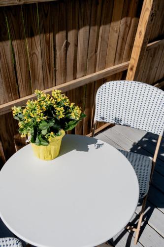 a white table with a vase of yellow flowers on it at Peaceful, modern, renovated, close to everything! in Gainesville
