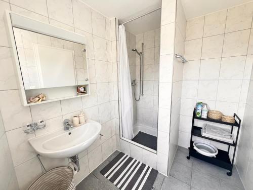 a white bathroom with a sink and a shower at Ferienwohnung SUN SAND SEA in Horn