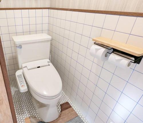 a bathroom with a white toilet in a tiled wall at 伊根の宿 汐風 Shiokaze in Nomuro