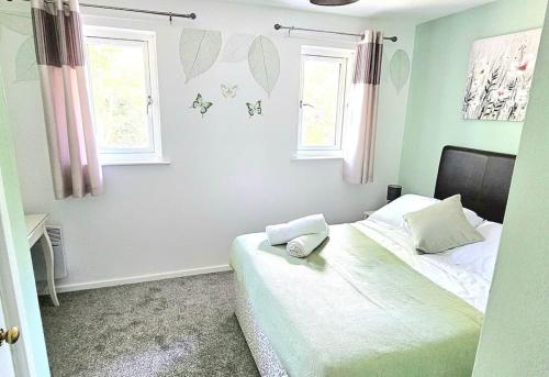 a bedroom with a bed with two pillows and two windows at Cozy 3-Bed House Near Willen Lake with Garden in Milton Keynes