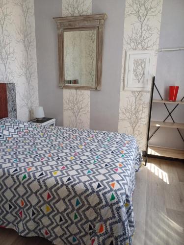 a bedroom with a bed with a quilt on it at Le Logis d'Elisa in Cosne Cours sur Loire