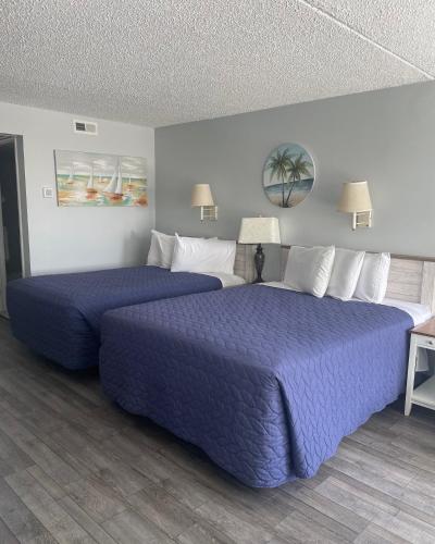 two beds in a hotel room with purple sheets at Acacia Beachfront Resort in Wildwood Crest