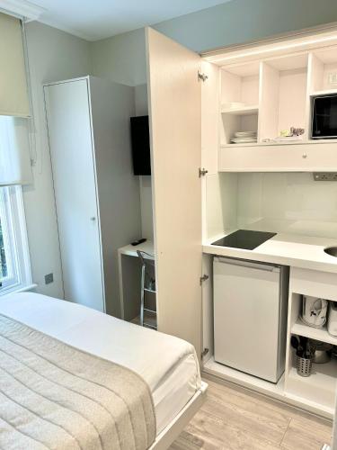 a white bedroom with a bed and a kitchen at NOX Richmond in Richmond