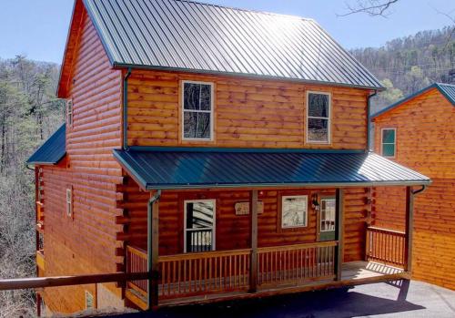 a log cabin with a porch and a metal roof at NEW BUILD-5BD-Hottub-WIFI-Theater-Pool Tble-ROKU in Pigeon Forge