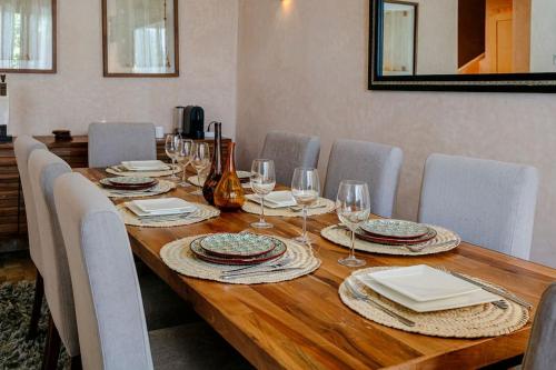 a long wooden table with chairs and wine glasses at Villa Atlas Harmony Marrakech in Marrakech