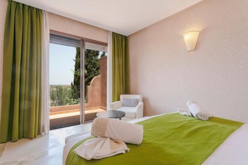 a bedroom with a green bed with a chair and a window at Villa Atlas Harmony Marrakech in Marrakech