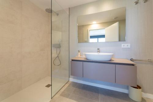 a bathroom with a sink and a glass shower at Oceans Oliva in Oliva