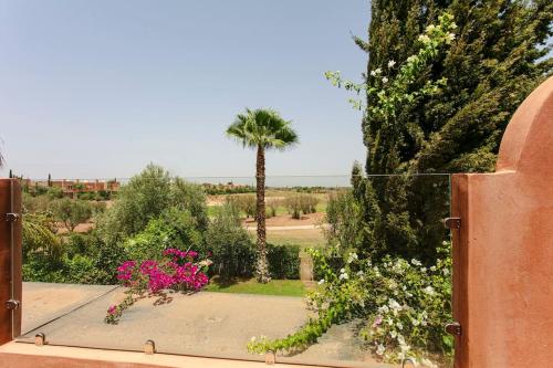 a view of a garden with pink flowers and a palm tree at Villa Atlas Harmony Marrakech in Marrakech