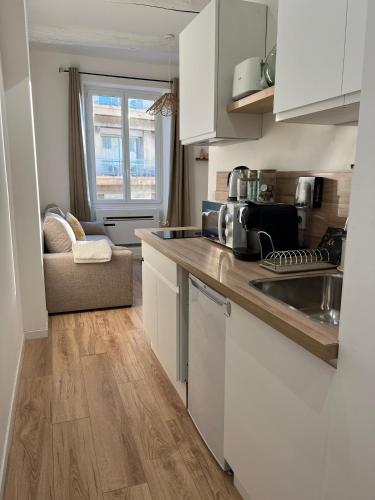 une cuisine avec des armoires blanches et un comptoir dans l'établissement Le Cocon du Vieux Port - Studio neuf tout confort en plein centre ville - Place aux Huiles, à Marseille