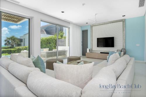 a living room with a white couch and a tv at Long Bay Beach Club in Long Bay Hills