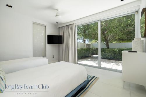 a bedroom with a white bed and a large window at Long Bay Beach Club in Long Bay Hills