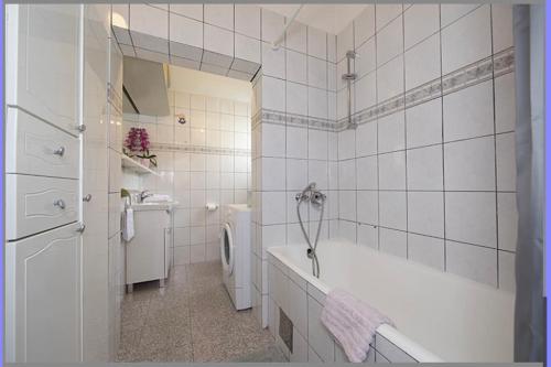 a white bathroom with a tub and a washing machine at Apartmani Milkovic in Tučepi