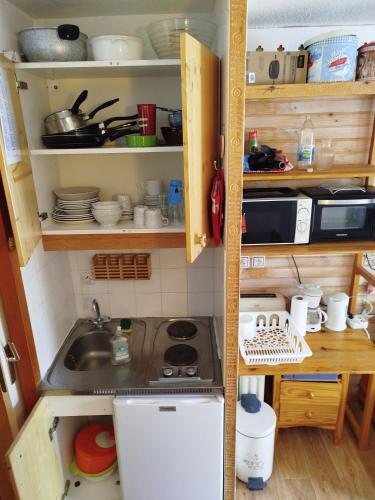 une petite cuisine avec un évier et une cuisinière dans l'établissement Studio chaleureux et cosy, à Valfréjus