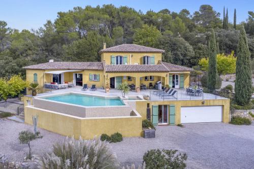 une grande maison jaune avec une piscine en face de celle-ci dans l'établissement Villa Les Etoiles by Villa Plus, à Lorgues