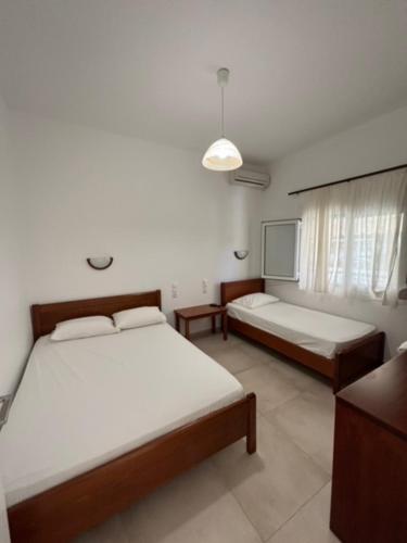 a bedroom with two beds and a table and a window at Anna -House Maria Manolaki, 2-Βedrm Apartment in Vourvourou