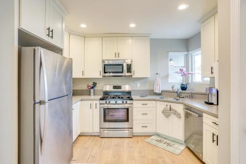 a kitchen with white cabinets and a stainless steel refrigerator at Fullerton Vacation Rental with Private Pool! in Fullerton