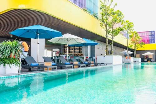 a swimming pool with chairs and umbrellas next to a building at Căn hộ Flamingo Hải Tiến in Thanh Hóa
