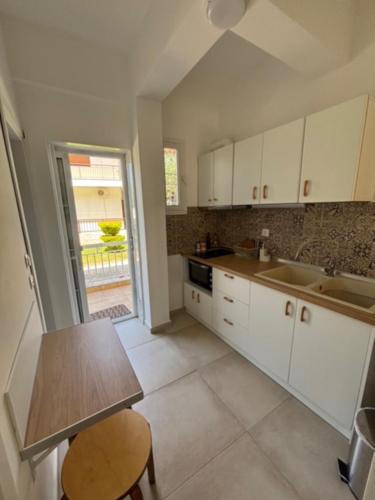 a kitchen with white cabinets and a table and a window at Anna -House Maria Manolaki, 2-Βedrm Apartment in Vourvourou