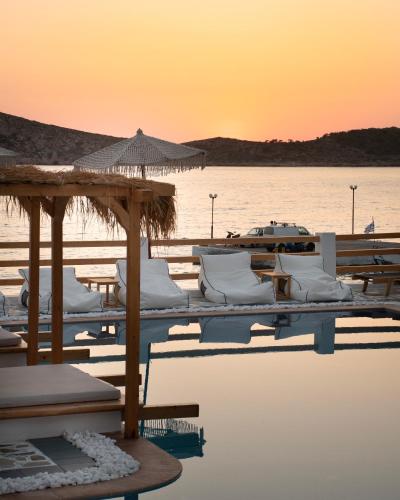 a group of white chairs and umbrellas in the water at SPONGIA HOTEL SUITES & Spa in Myrties