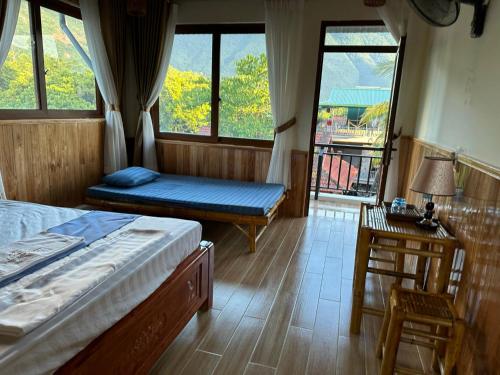 a bedroom with two beds and a table and a window at Mai Châu Homestay 88 in Mai Chau
