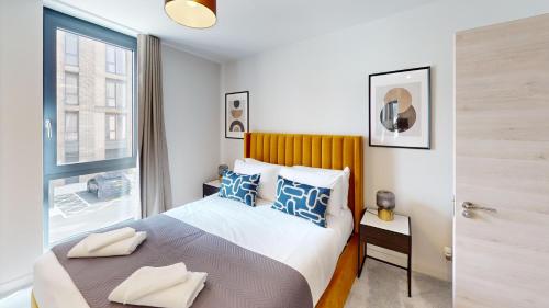 a bedroom with a bed with blue pillows and a window at Charles Hope Brighton & Hove in Brighton & Hove