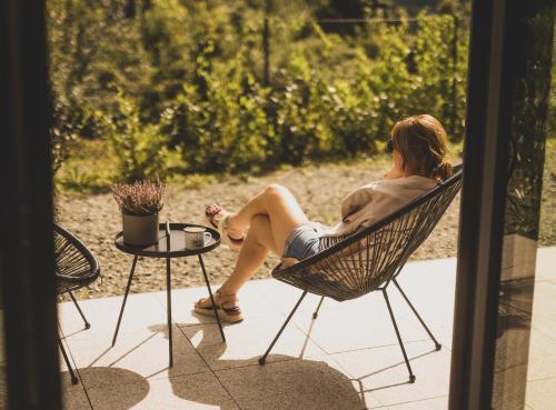 a woman sitting in a chair on a patio at Sowie Chatki - domki z widokiem na Góry Sowie in Sokolec