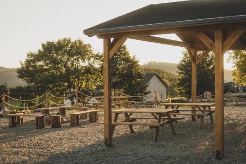 a group of picnic tables under a wooden pavilion at Sowie Chatki - domki z widokiem na Góry Sowie in Sokolec