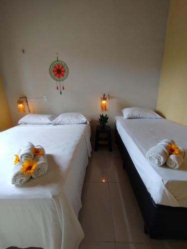 two beds in a room with white sheets and flowers on them at Villa dos Coqueirais in Icaraí