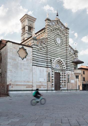 a person riding a bike in front of a building with a clock tower at Piazza Duomo - 20 min by train to Florence in Prato