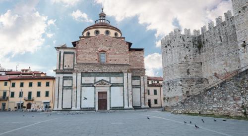 a large brick building with a tower next to two castles at Piazza Duomo - 20 min by train to Florence in Prato
